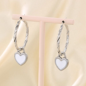 Detailed shot of silver twist hoop earrings with white enamel heart charms on a stand