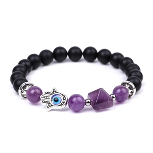 Macro shot of Hamsa Hand charm with Evil Eye on amethyst and matte black bead bracelet