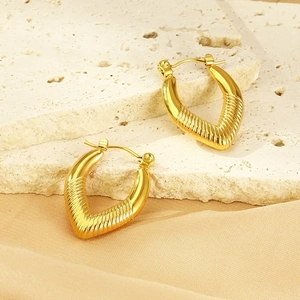 Detail of gold V-shaped huggie earrings with diamond pattern on natural stone