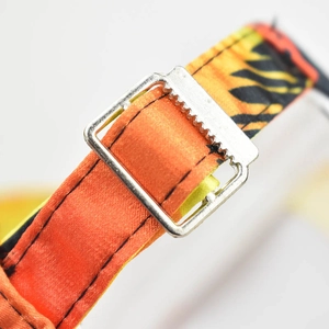 Close-up of bright orange strap with black flame pattern and silver metal buckle slider