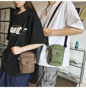 Detail of dark brown and olive green canvas messenger bags with adjustable straps