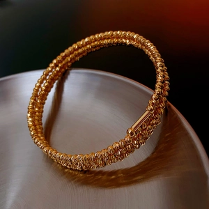 Macro detail of triple-layer gold beaded bracelet with diamond-cut metal texture