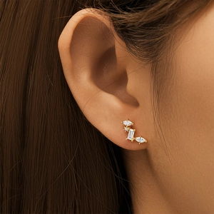 Close-up of gold stud earring with marquise and rectangular white zircons on ear