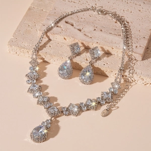 Macro detail of silver zircon necklace and water drop earrings on stone base