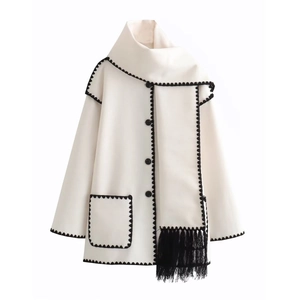 Detail of ivory wool coat with black crochet wavy edges and matching tasseled scarf