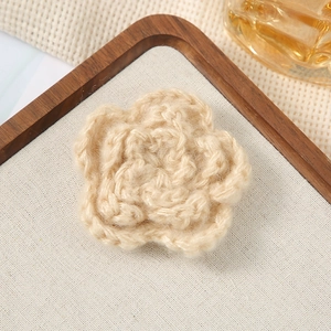 Close-up of a 7cm beige crochet flower accessory on a rustic wooden and fabric background