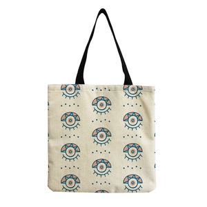 Detail of canvas shopping bag with evil eye print pattern and black shoulder straps