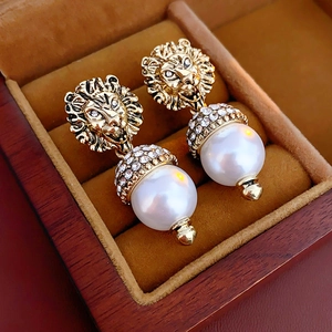 Detail of vintage lion head pearl earrings with rhinestone accents in a velvet box