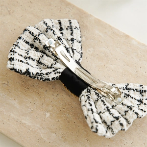 Detail view of the silver metal clip and black and white tweed texture on hair bow