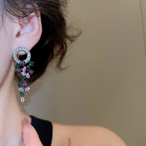 Macro side view of silver drop earrings with purple and green teardrop crystals on model