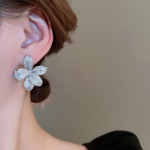Close-up of elegant flower stud earrings with shimmering rhinestones on model's ear