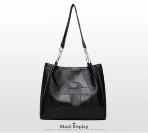 Detail of black PU leather tote bag with unique patchwork design and metal chain strap