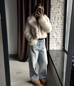 Short faux fox fur coat in off-white styled with wide-leg jeans and platform shoes