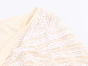 Detail of elegant sequin patterns on beige mesh fabric for a luxury evening gown