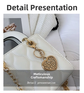 Close-up of white quilted leather bag showing gold heart charm and fine stitching details