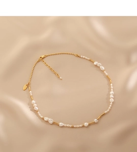 Detail of baroque freshwater pearl necklace with gold beads on champagne silk background
