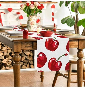 Detail of red cherry printed linen table runner on a wooden dining table centerpiece