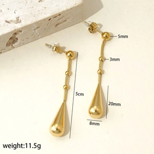 Close-up of golden stainless steel drop earrings with bead and snake chain details