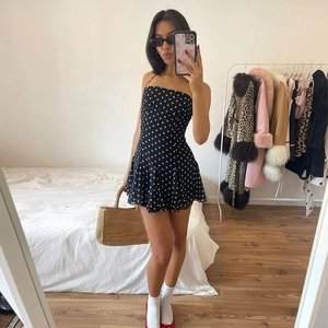 Chic black polka dot mini dress with strapless design and ruffled hem detail for summer