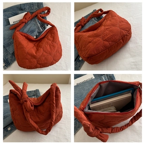 Detail view showing quilted texture and knot design of the large orange shoulder bag