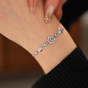 Detail of silver bracelet with blue snowflake charm and zircon stones worn on wrist