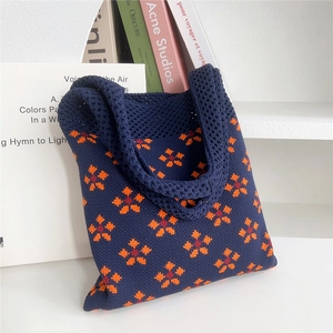 Dettaglio della borsa in maglia blu scuro con ricamo floreale arancione in morbida lana