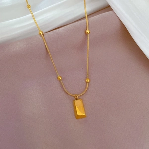 Detail showing gold rectangle bar pendant on delicate beaded snake chain necklace