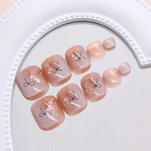 Pink gradient toe press-on nails with black bow patterns and fine gold glitter