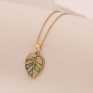 Macro shot of gold-plated leaf pendant with colorful enamel and sparkling rhinestones