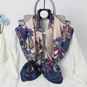 Detail of navy blue paisley satin scarf tied on white shirt collar for elegant styling