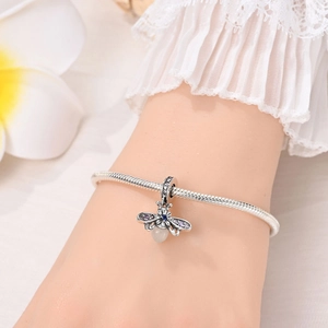 Detail of silver snake chain bracelet featuring glowing bee pendant with purple zircons