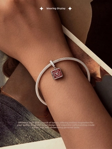 Close-up of s925 silver mesh bracelet with red enamel book pendant on a magazine background
