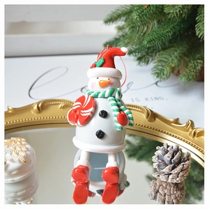 Detail view of festive snowman hanging ornament with red hat and striped scarf