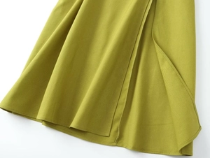 Detail view of the high-slit hem and sewing craft on a grass green midi skirt
