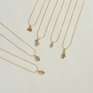 Detail of 14K gold plated necklaces featuring shell and fruit charms with zircon stones