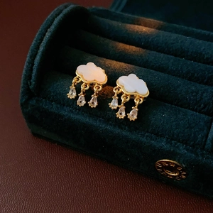 Macro detail of cloud and raindrop stud earrings with gold base on green velvet