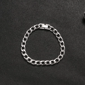 Detail of silver titanium steel Cuban link bracelet with jewelry clasp on black texture