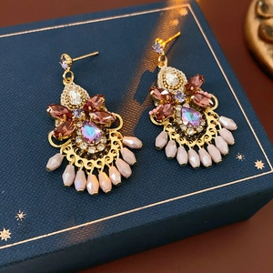 Macro shot of vintage crystal earrings with purple gems and beige water drop fringe detail