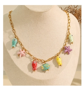 Golden ocean theme necklace with colorful fish and star charms on jewelry stand