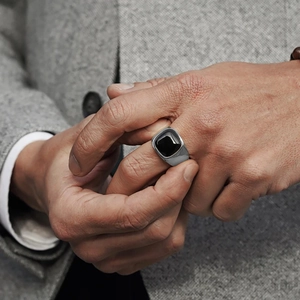 Close-up of men's square black onyx ring with silver band paired with a business suit