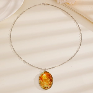 Detail van ovale glazen hanger ketting met religieuze kunst op witte textuurachtergrond
