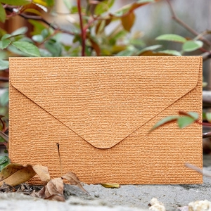 Brown linen textured mini kraft paper envelope for cards on natural leaf background
