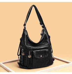 Detail view of black soft leather crossbody bag with multiple pockets and silver zippers