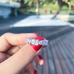 Detail of a 925 silver ring featuring mixed-cut moissanite stones on a person's hand
