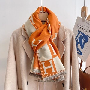 Detail of orange and beige cashmere pashmina featuring geometric H pattern and fringes