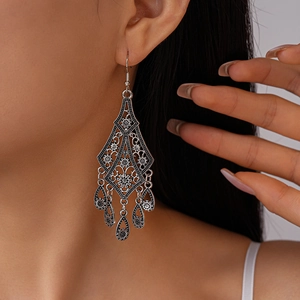 Macro shot of silver bohemian hollow flower teardrop tassel earrings worn by a model