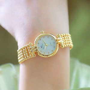 Luxury gold women's quartz watch with green dial and crystal markers on model wrist