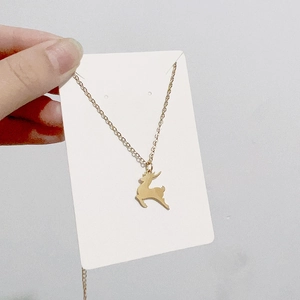 Gros plan d'un collier pendentif renne doré sur carte blanche tenu par la main