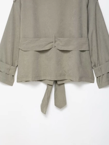 Close-up of gray-green faux suede jacket back with tiered storm flap and waist ties