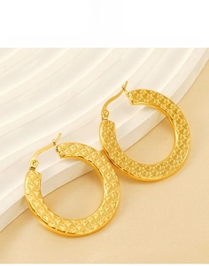 Macro detail of gold titanium steel hoop earrings with starburst hammered texture